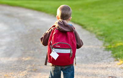 Young boy walking to school with backpack