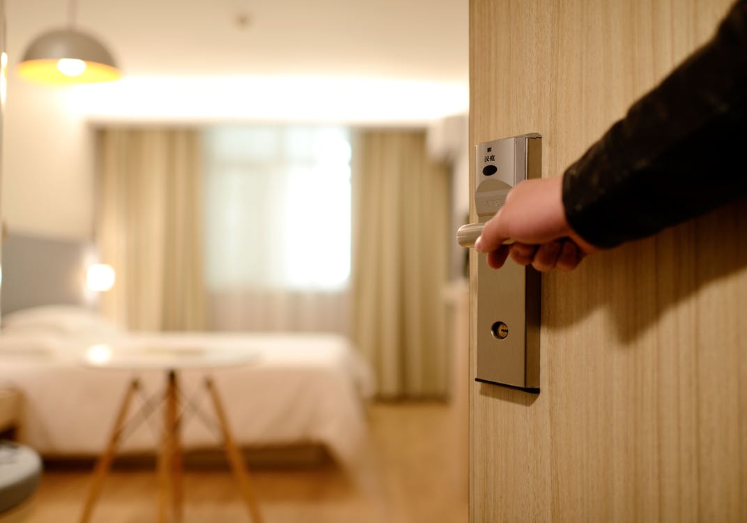 Person opening door handle into hotel room.