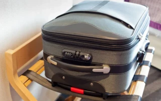 Suitcase in a hotel room sitting on a suitcase rack.