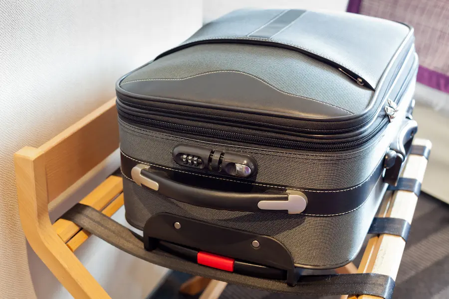 Suitcase in a hotel room sitting on a suitcase rack.