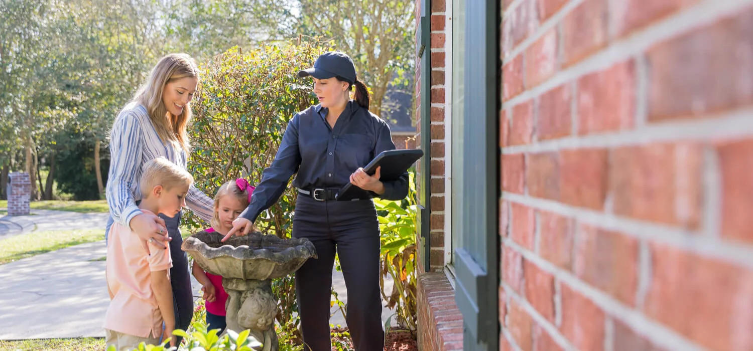 Pest technician helping mother and daughter outside their Wisconsin residential home.
