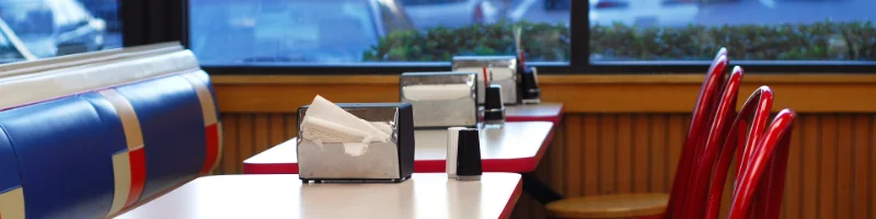 Closeup of a table with napkins on it, inside a fast food restaurant. 